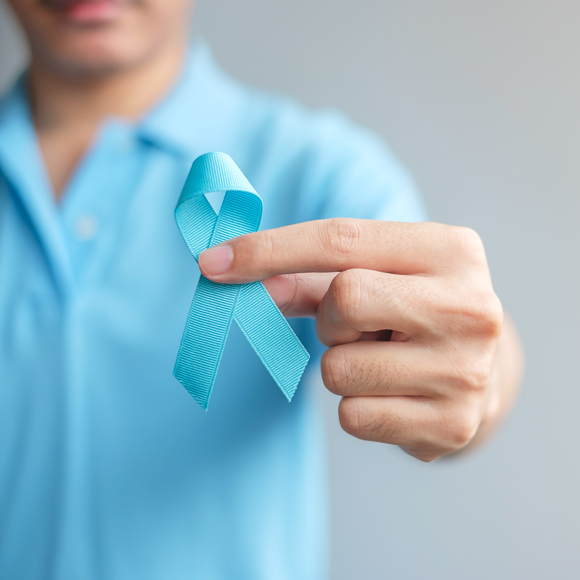 November Prostate Cancer Awareness month, Man in blue shirt with hand holding Blue Ribbon