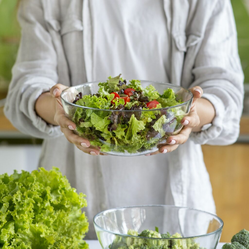 Woman holding bowl with fresh salad of roasted vegetables